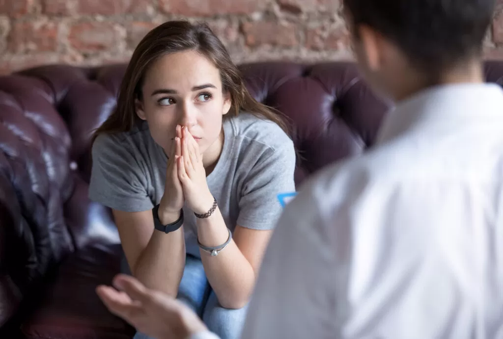 A young girl holding her hands in front of her face during a session with her anxiety therapist.