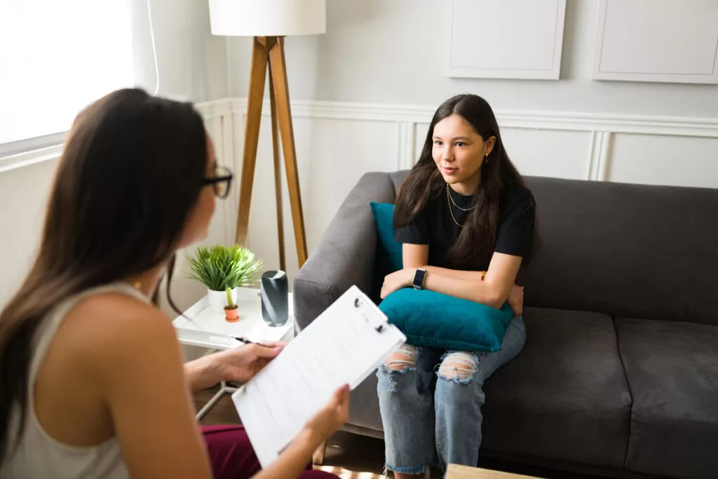 An anxiety therapist speaking with a teenager sitting on a couch in Chicago.