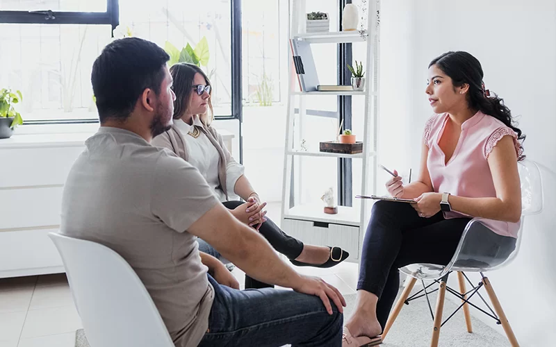 Couples Therapy - Hispanic young woman psychologist with couple patient in therapy talking