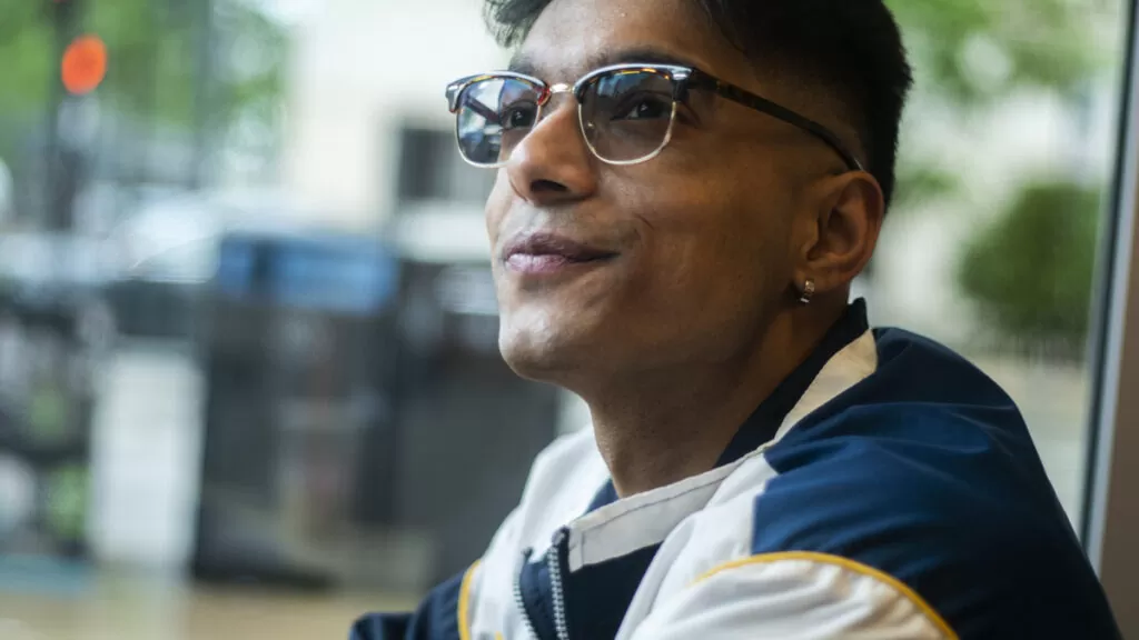 A person wearing glasses smiling and looking to the side in Chicago.